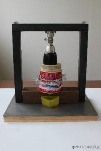 自家製ミニ搾油器で椿油をしぼっている写真